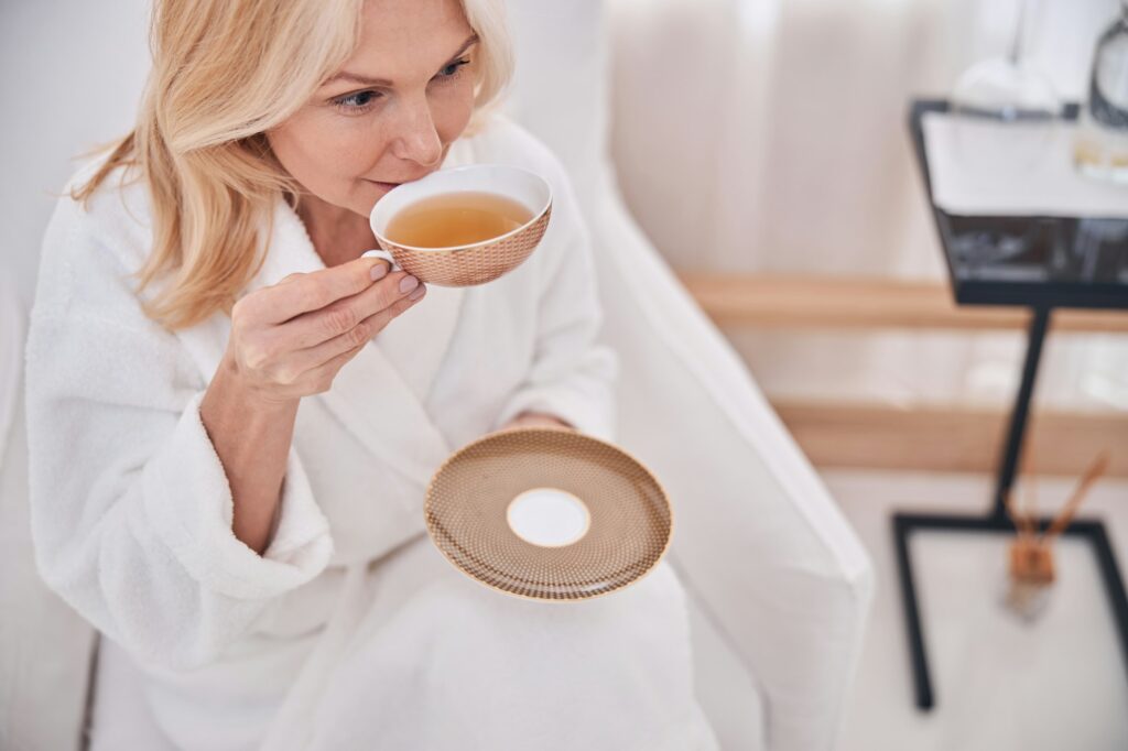 Pensive woman taking a sip of chamomile tea