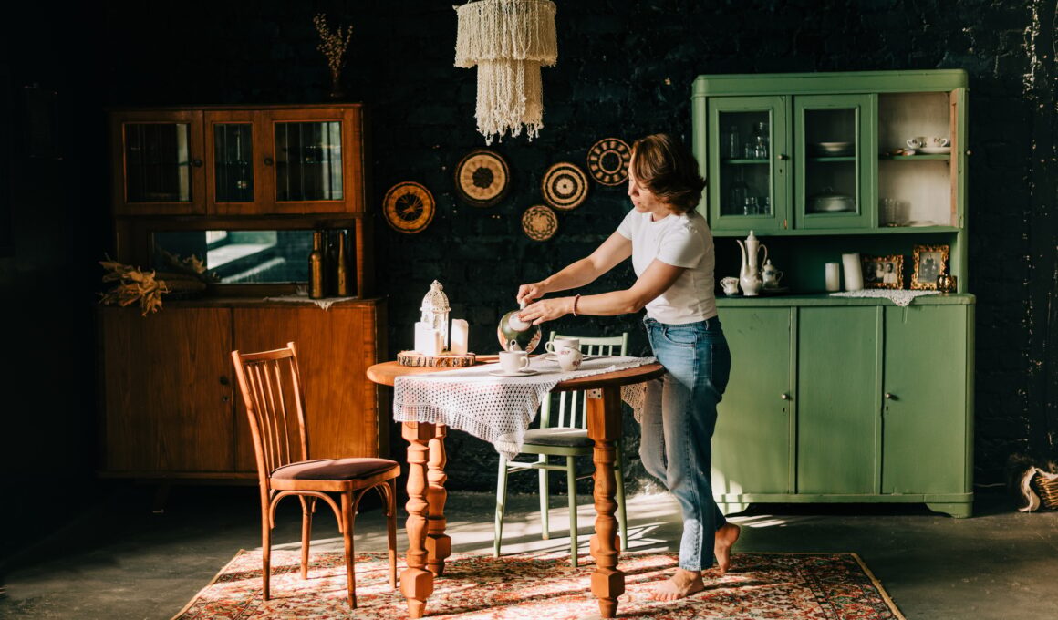 Young woman with red hair staying at the kitchen and preparing a tea indoors in beautiful interior