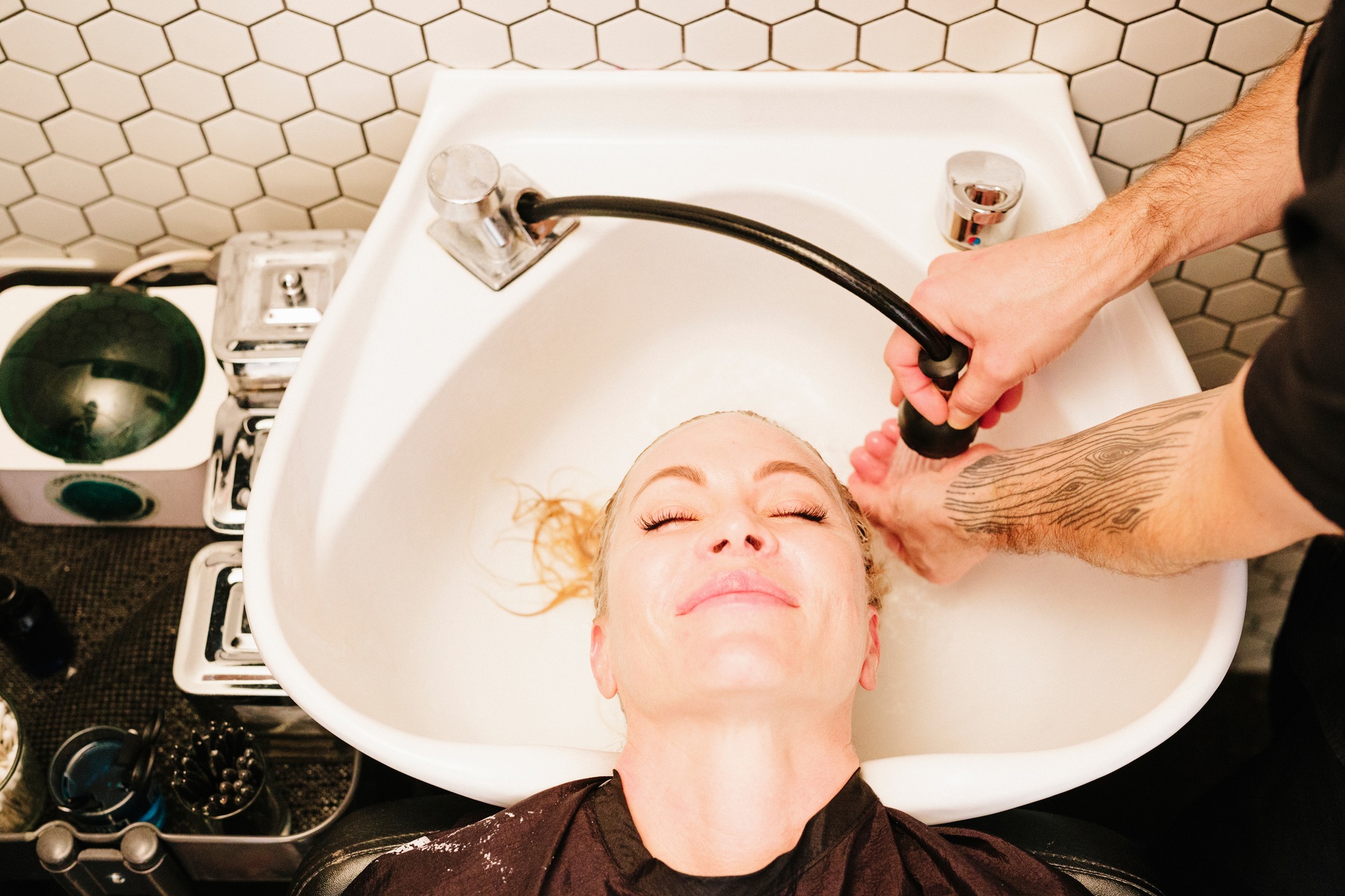 A female client at a hair salon, having her hair rinsed in a basin.